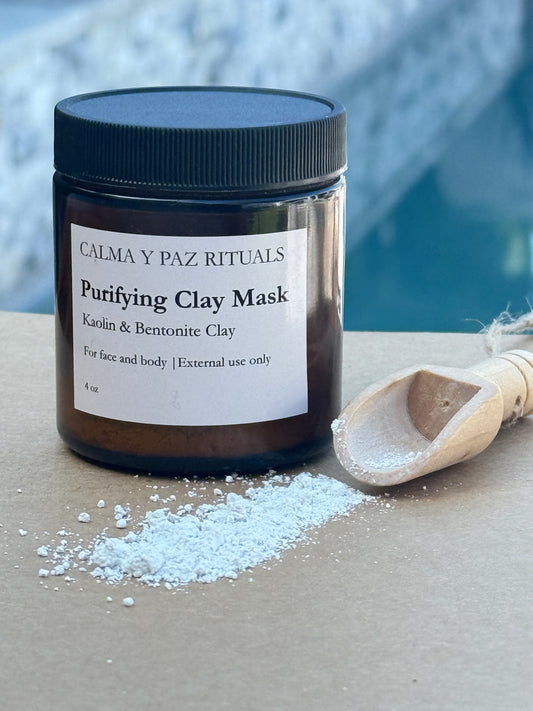 Jar of Calma y Paz Rituals Purifying Clay Mask with a scoop of white powder on a neutral background. Kaolin and Bentonite clay.